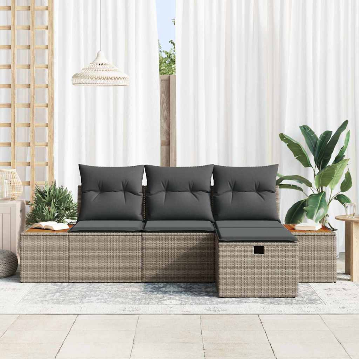 Rattan-Gartensofa mit grauen Kissen, weißen Vorhängen und Topfpflanze auf einer Terrasse.