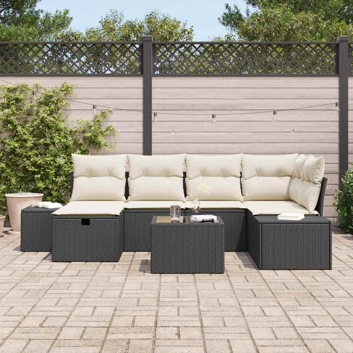 Ein Outdoor-Ecksofa mit cremefarbenen Kissen und einem dunklen Korbgewebe. Zwei passende quadratische Tische und eine gepflasterte Terrasse.
