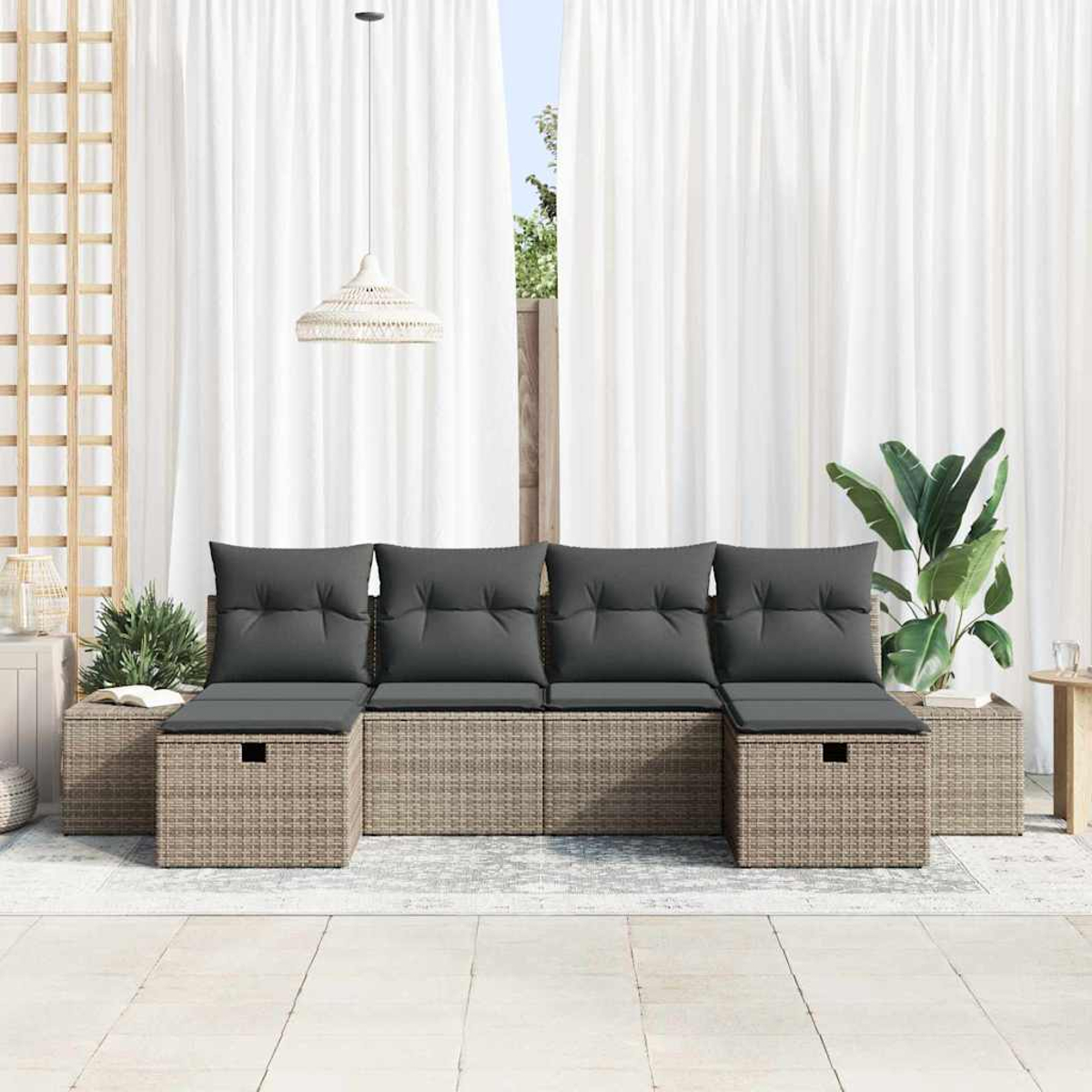 Sitzbereich im Freien mit einem Rattan-Sofa, grauen Kissen und einem weißen Vorhang im Hintergrund.