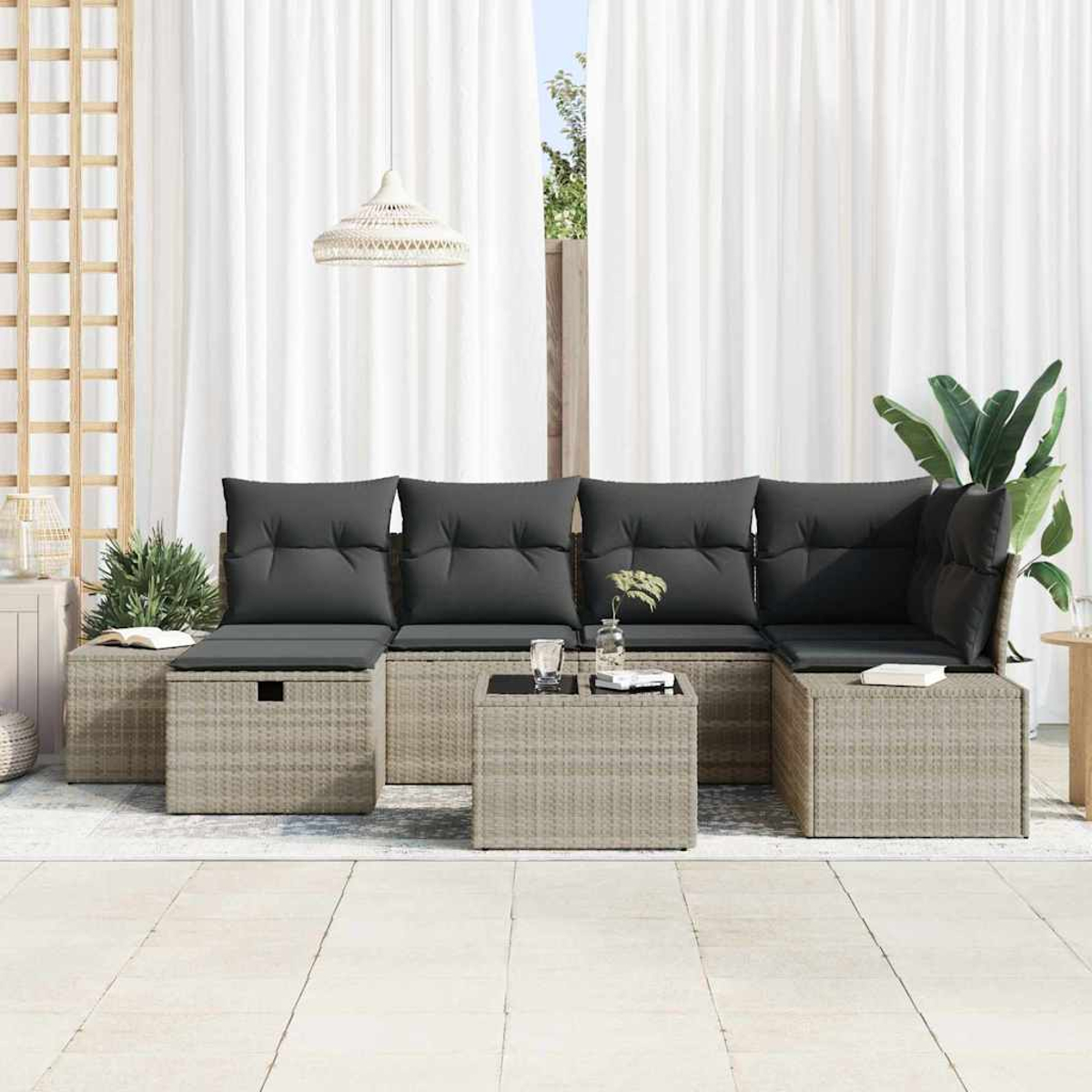 Outdoor-Ecksofa mit grauen Kissen. Inklusive kleinem Tisch mit zwei Gläsern und einer Pflanze. Weiße Vorhänge und eine Pflanze im Hintergrund.