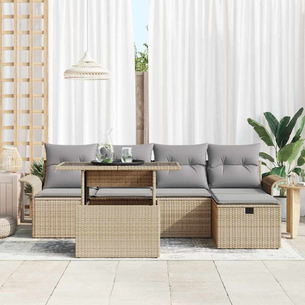 Gartenmöbel-Set aus Korbgeflecht mit grauen Kissen und einem Tisch mit Glasplatte. Weiße Vorhänge und eine Pflanze im Hintergrund.