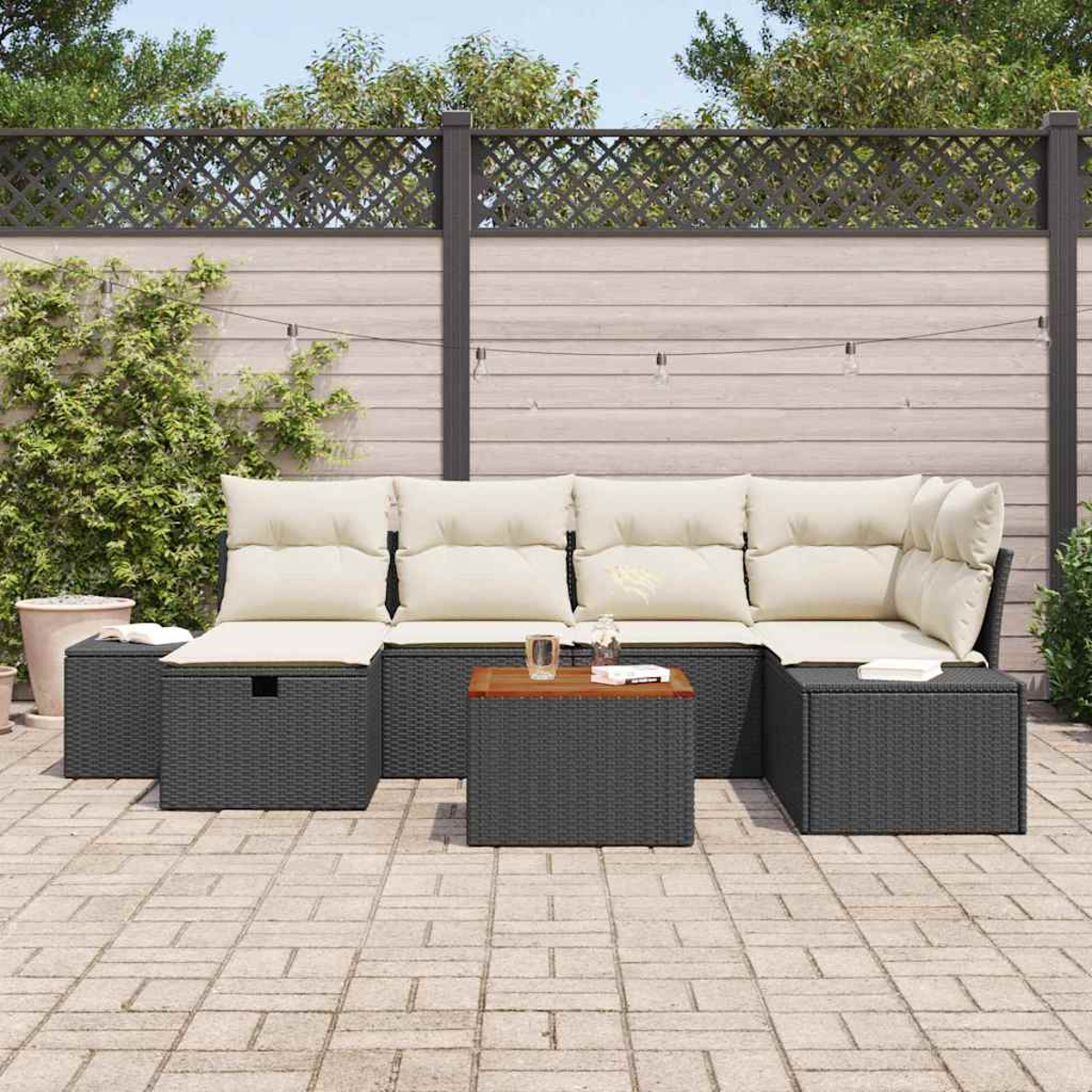 Ein Ecksofa im Freien mit cremefarbenen Kissen und einem dunkelgrauen, gewebten Rahmen. Ein kleiner Holztisch und ein Gitterzaun sind im Hintergrund.