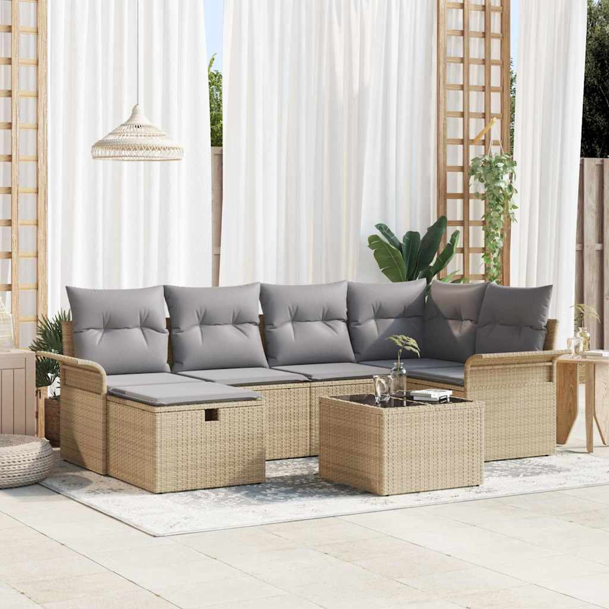 Garten-Sitzgruppe: Korbsessel mit grauen Kissen und einem passenden Couchtisch auf hellem Teppich. Weiße Vorhänge und Pflanzen im Hintergrund.