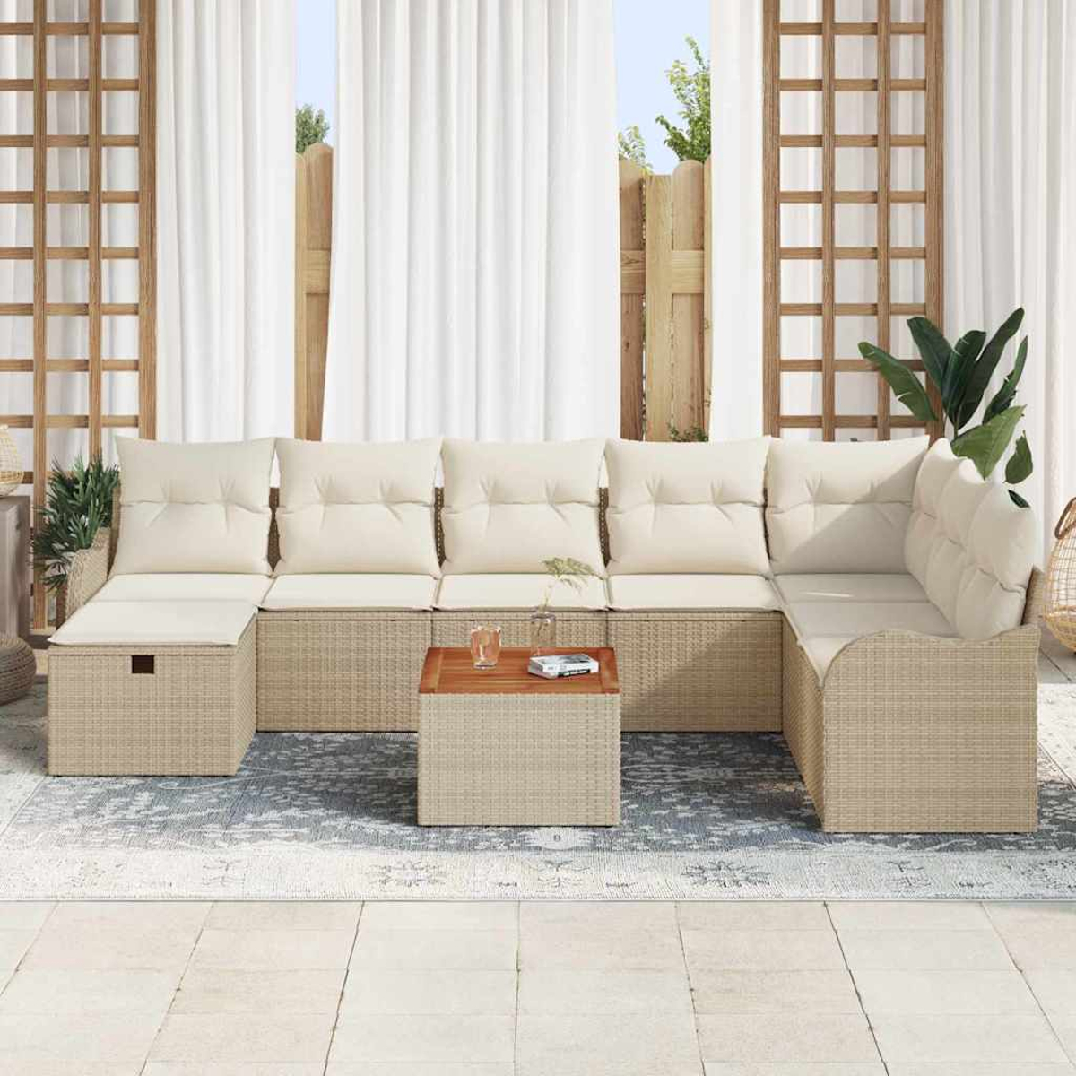Sofá seccional para exteriores con cojines color crema. Una mesa de madera con bebidas está delante. Cortinas blancas y plantas visibles.