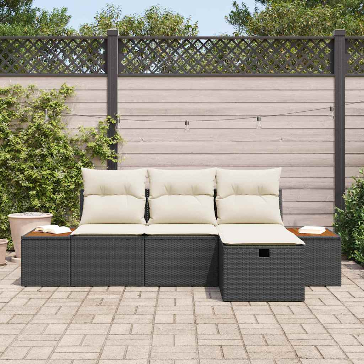 Terrassenmöbel im Freien mit cremefarbenen Kissen. Dahinter ein Holzzaun mit Kletterpflanzen und eine Ziegelterrasse.