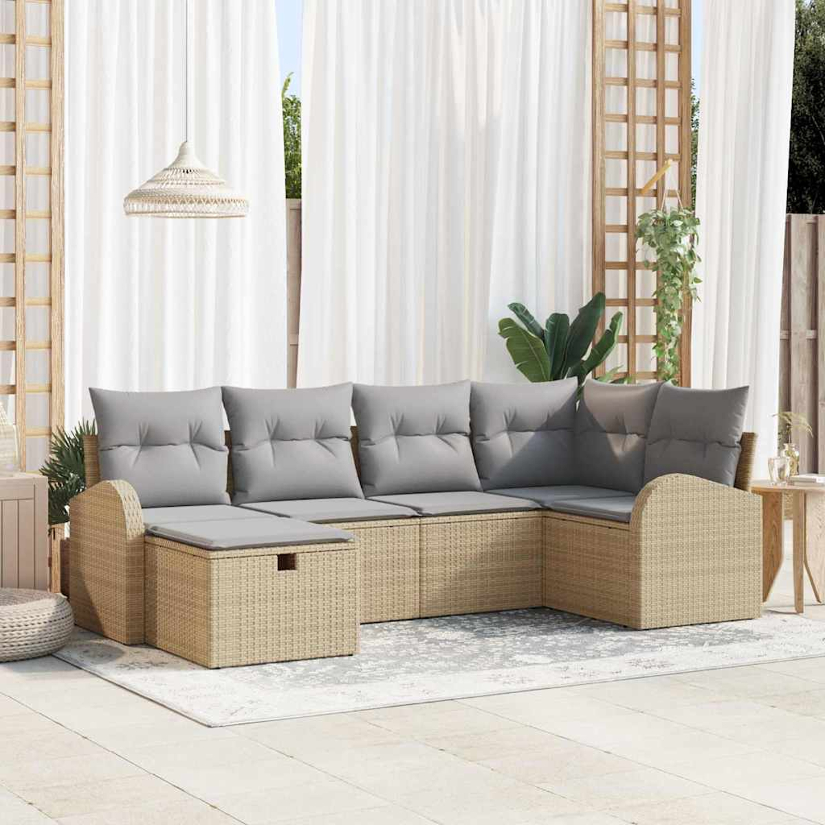 Ein Sitzbereich im Freien mit einem Ecksofa aus Korbgeflecht, grauen Kissen, weißen Vorhängen und einer Hängelampe.