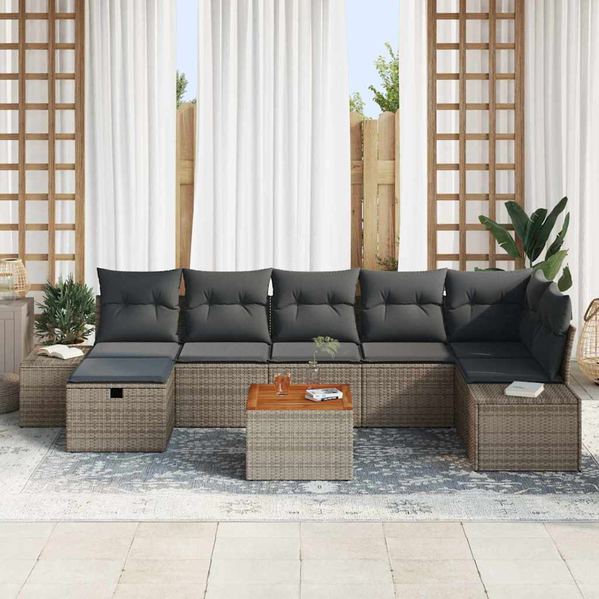 Ein Ecksofa für den Außenbereich mit grauen Kissen. Vorne steht ein Holztisch. Weiße Vorhänge und ein Spalier dahinter.