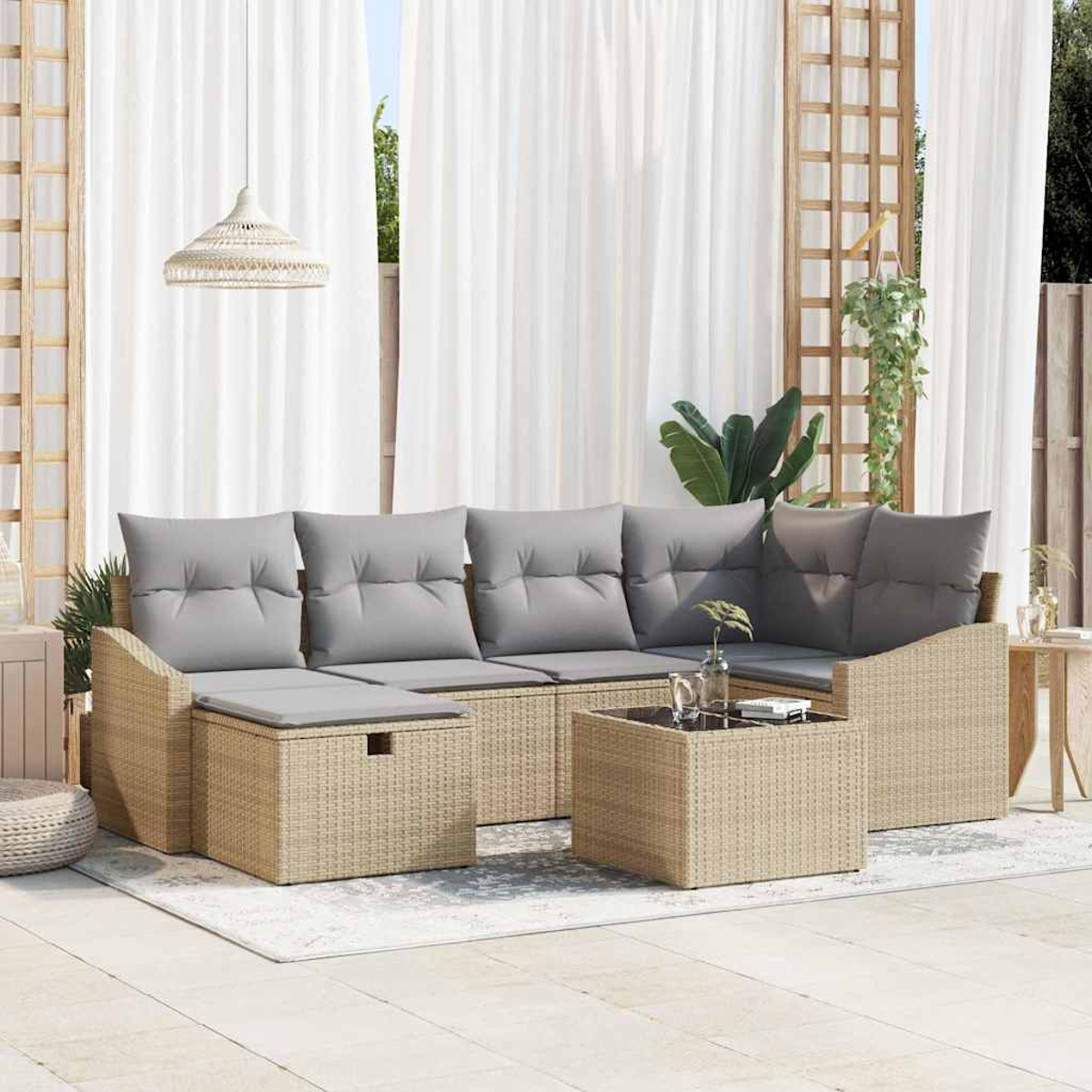 Rattan-Sofa im Freien mit grauen Kissen und einem Couchtisch. Weiße Vorhänge und eine Hängelampe sind im Hintergrund.