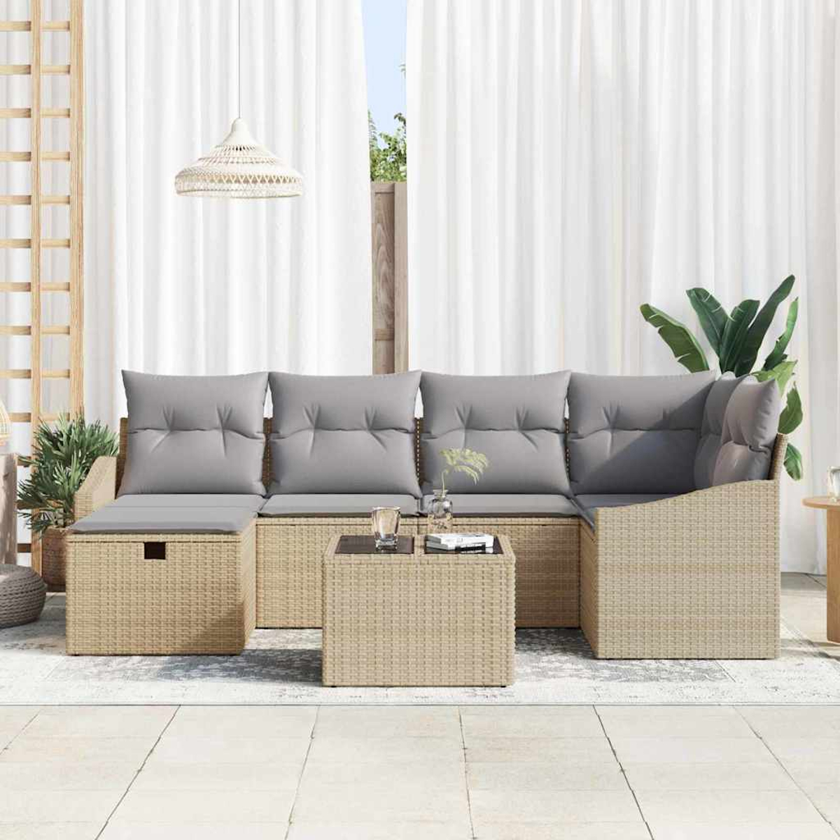 Outdoor-Korbsessel mit grauen Kissen und Couchtisch. Weiße Vorhänge im Hintergrund. Pflanzen und eine Hängelampe sind sichtbar.
