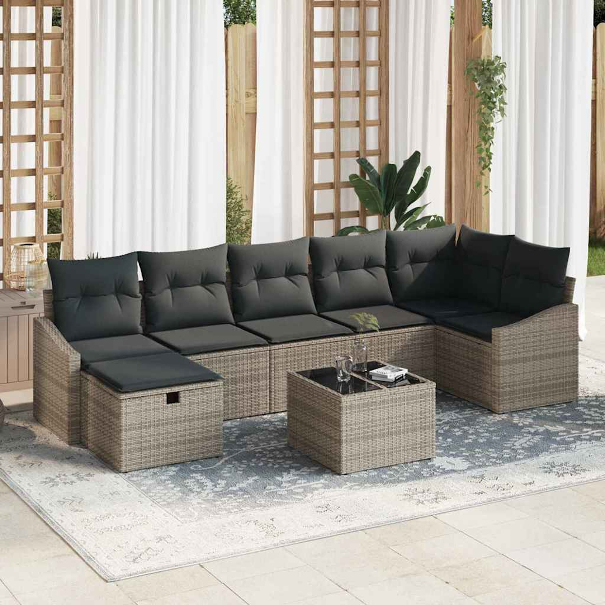 Outdoor-Ecksofa mit grauen Kissen und einem kleinen Tisch auf einem gemusterten Teppich, weißen Vorhängen und Holzgitter.