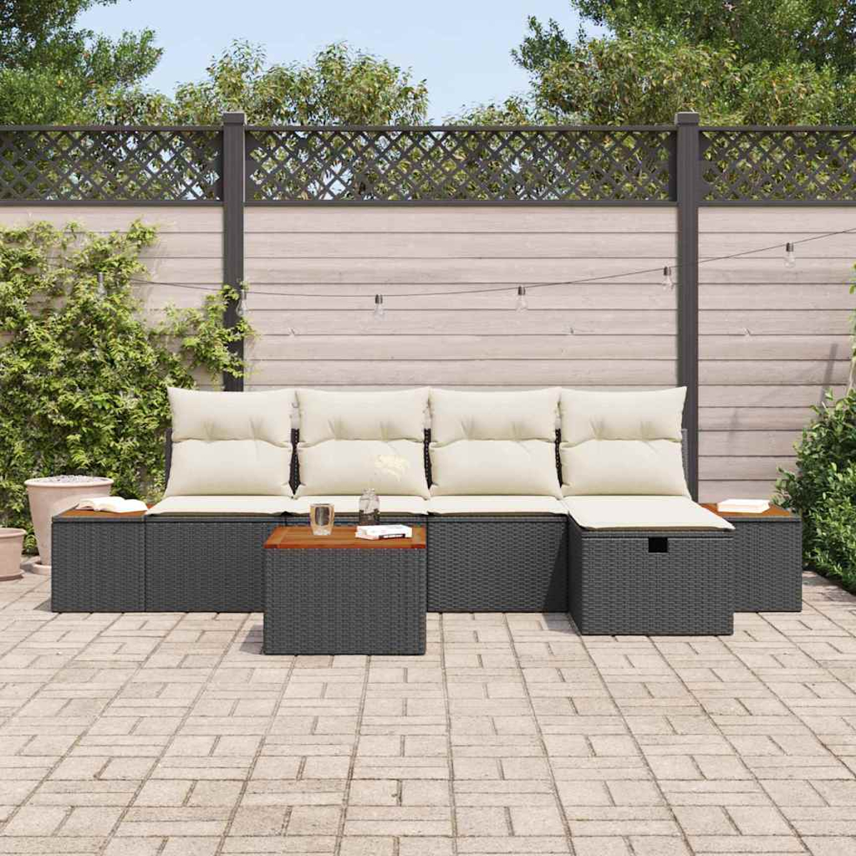 Garten-Sitzgruppe mit cremefarbenen Kissen, dunkelgrauer Webstruktur und Holztischen. Auf gepflasterter Terrasse, mit Zaun und Grün.