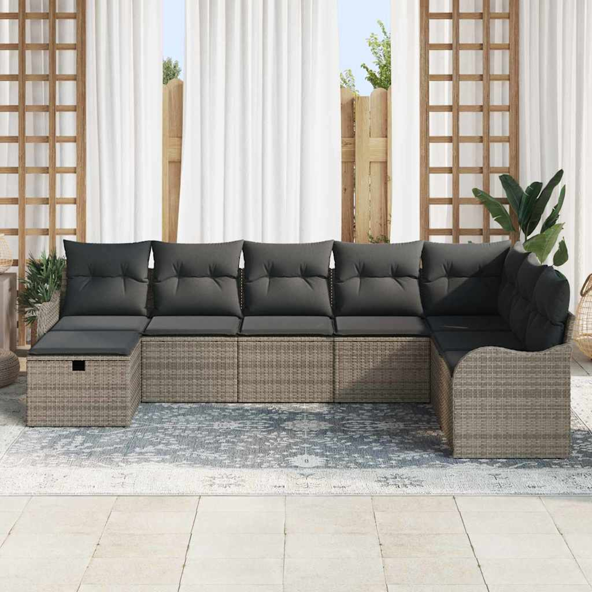 Outdoor-Ecksofa mit grauen Kissen auf einem gemusterten Teppich. Weiße Vorhänge und Holzgitter im Hintergrund.