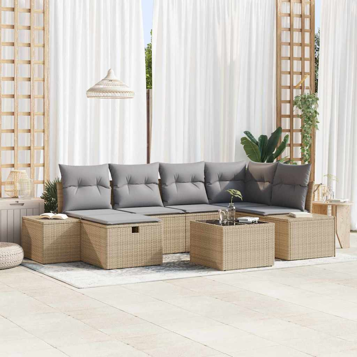 Outdoor-Sitzbereich mit beigen Rattanmöbeln, grauen Kissen, einem Tisch mit Glasplatte und weißen Vorhängen im Hintergrund.