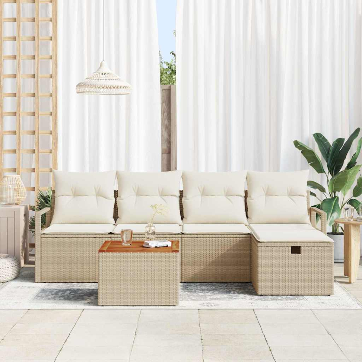 Un sofá exterior de mimbre beige con cojines crema, mesa de centro y una planta. Cortinas blancas y una pantalla de madera en el fondo.