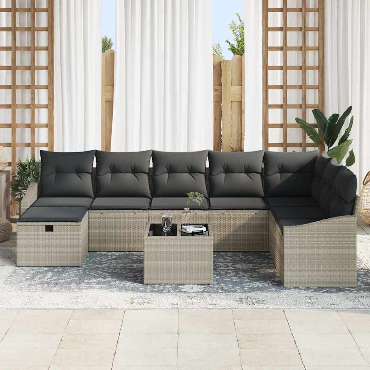 Sofá seccional exterior con cojines grises y una mesa pequeña. Detrás cortinas, celosías de madera y una valla.