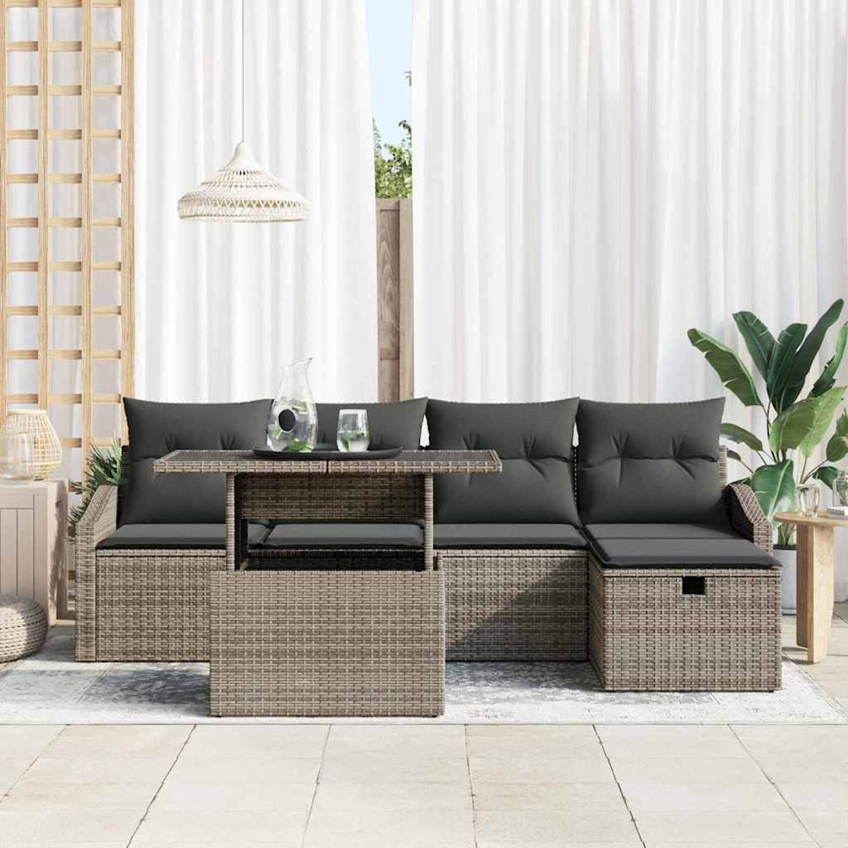 Garten-Sitzgruppe mit grauen Kissen, Tisch mit Krug und weißen Vorhängen im Hintergrund.