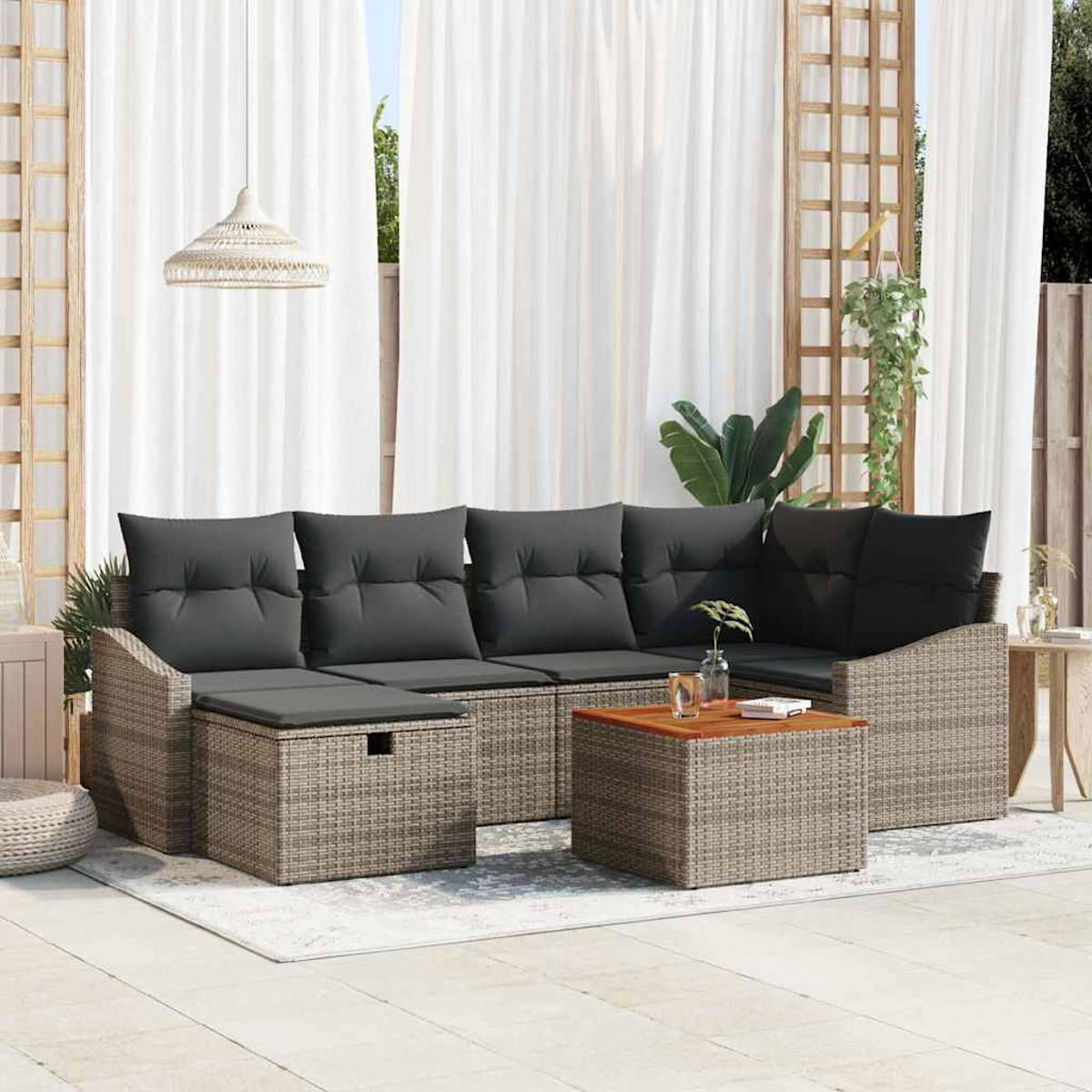 Gartenmöbelset mit grauen Kissen, einem Holztisch und weißen Vorhängen im Hintergrund. Eine entspannte Umgebung im Freien.