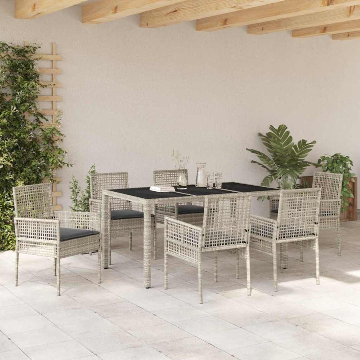 Essgruppe im Freien: Tisch mit sechs Stühlen, Grünpflanzen und einer hellen Terrasse. Der Tisch hat eine schwarze Platte.