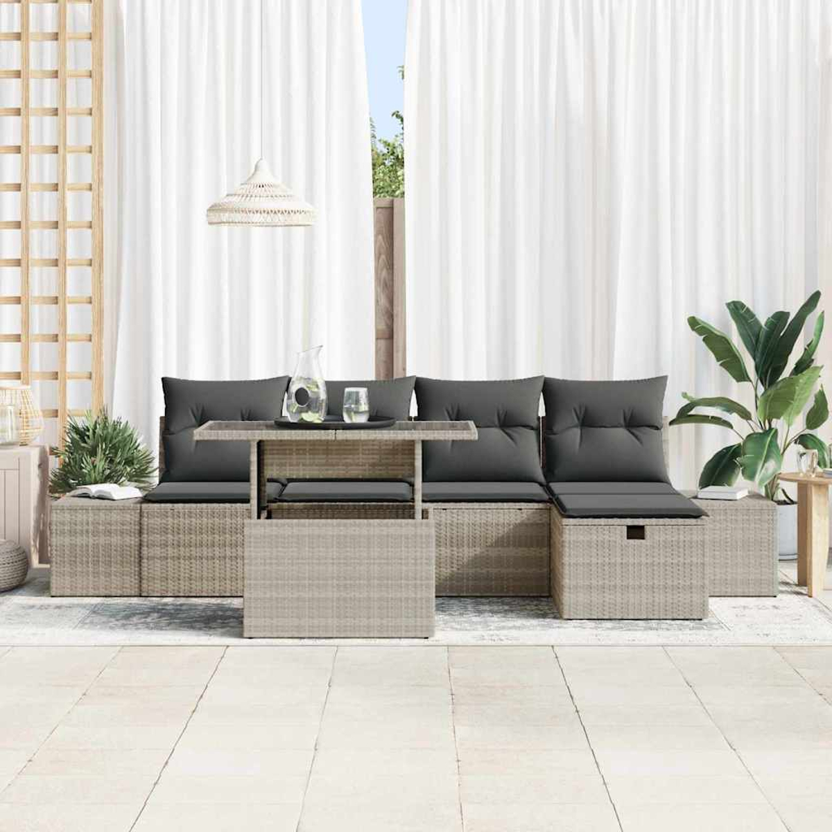 Outdoor-Sitzgruppe mit grauen Kissen und einem Tisch. Weiße Vorhänge im Hintergrund, rechts eine große Pflanze. Neutrales Farbschema.