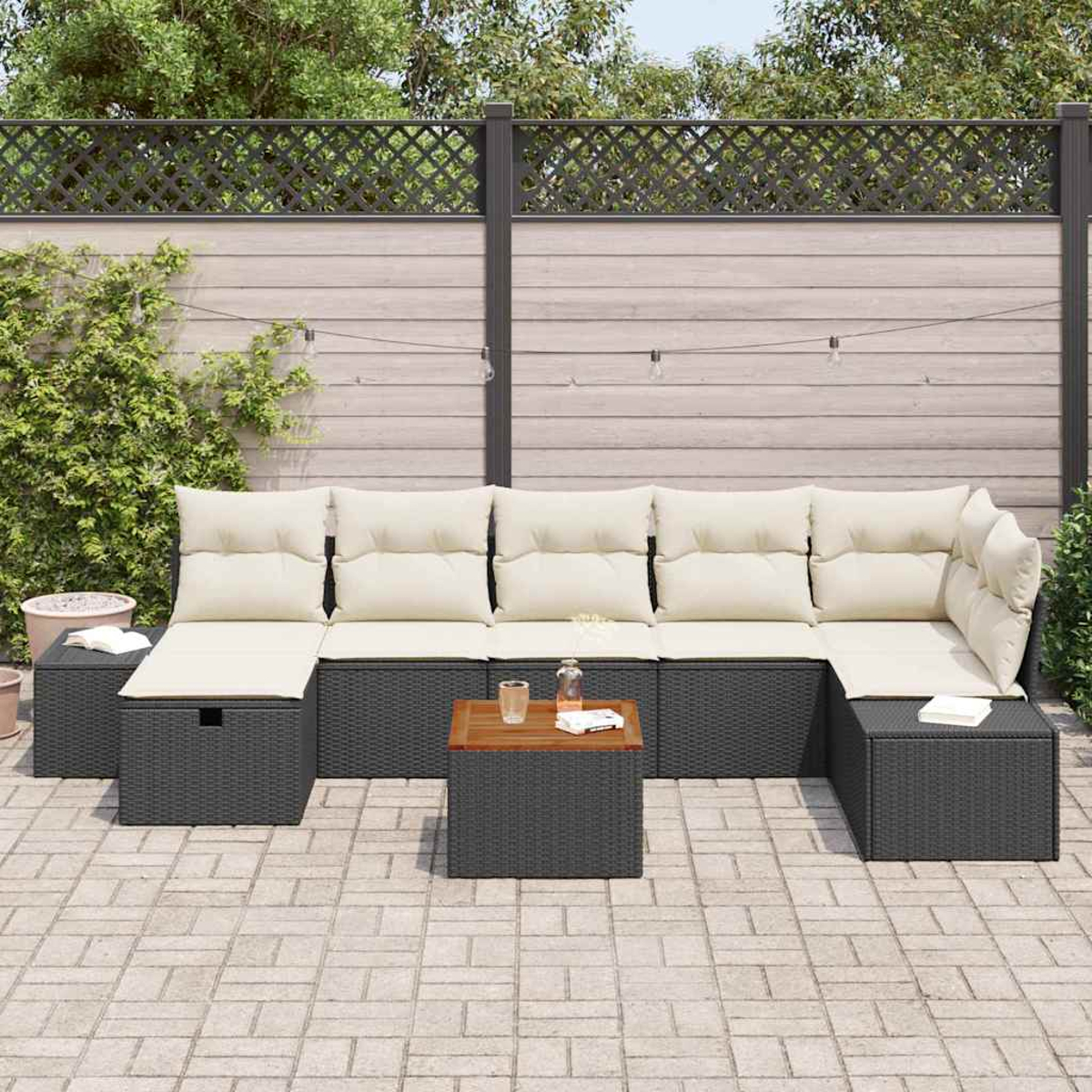 Graues Ecksofa mit cremefarbenen Kissen und einem Holztisch im Freien auf einer Ziegelterrasse. Im Hintergrund ein Holzzaun.