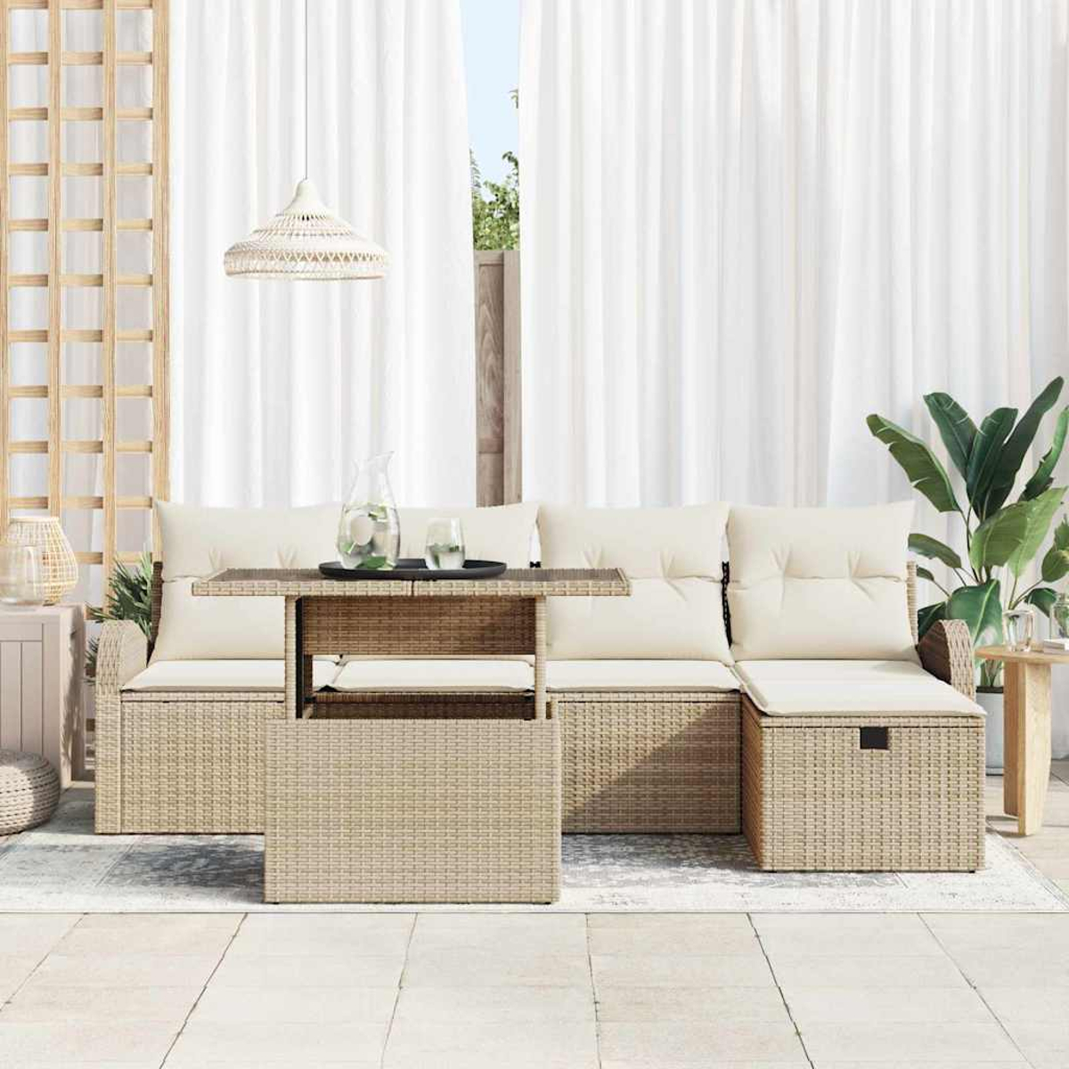 Gartenmöbel-Set. Korbssofa mit cremefarbenen Kissen und Tisch. Weiße Vorhänge im Hintergrund.