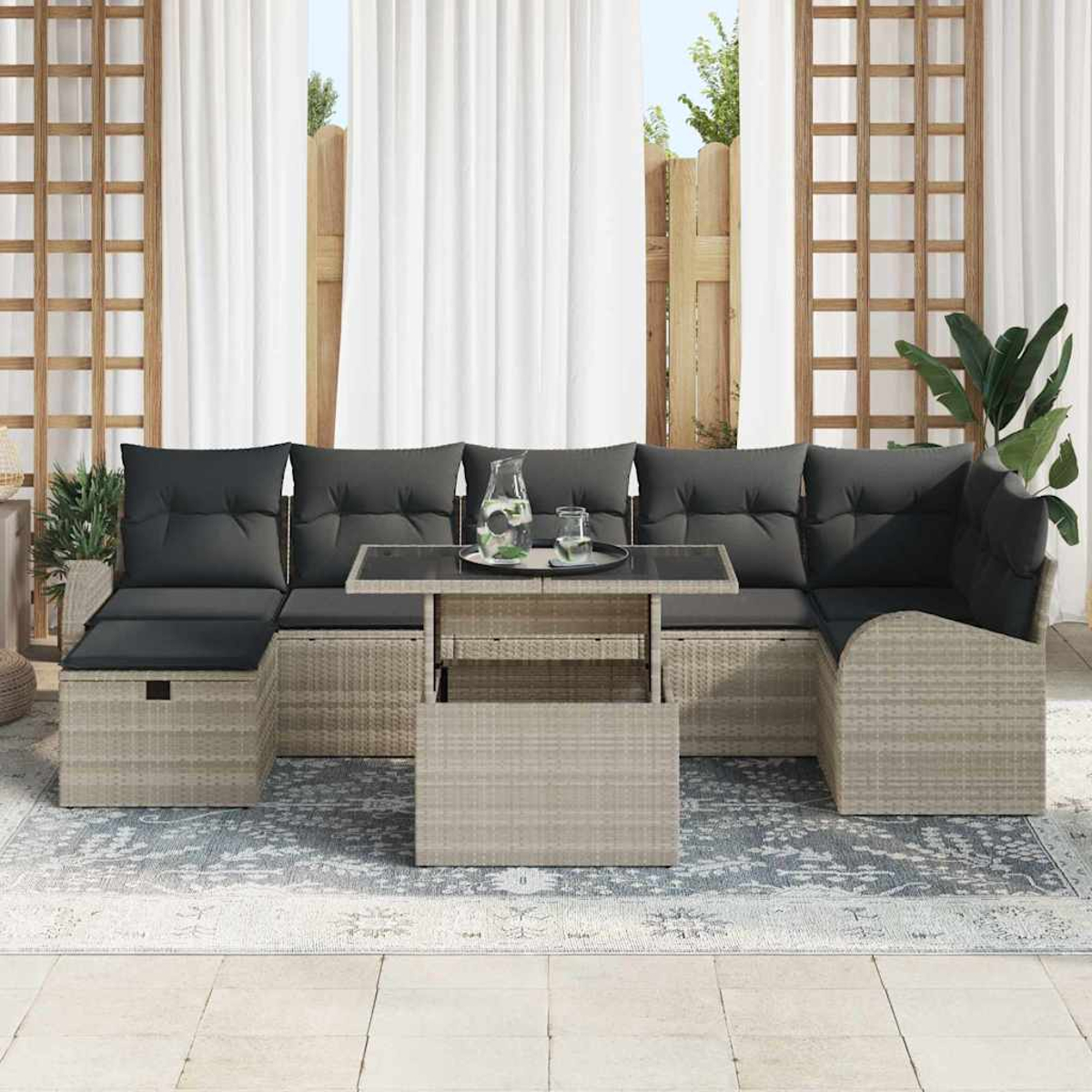 Outdoor-Ecksofa mit dunklen Kissen, Glastisch und Teppich. Weiße Vorhänge und Holzgitter im Hintergrund.