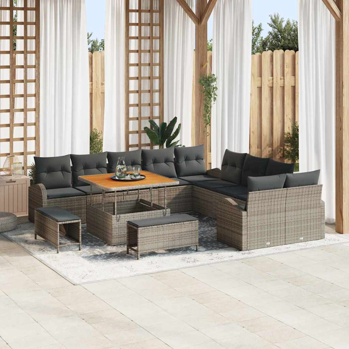 Outdoor-Sitzbereich mit Korbmöbeln, grauen Kissen, Holztisch und weißen Vorhängen. Enthält einen Teppich und einen Holzzaun.