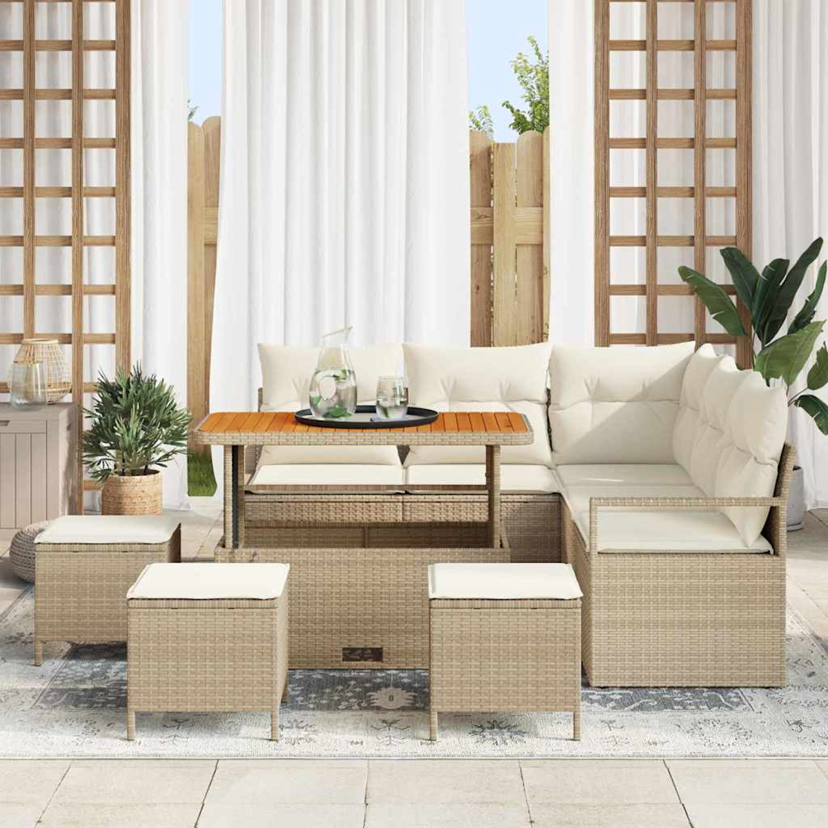 Set di mobili da esterno in vimini. Include un divano componibile con cuscini, un tavolo e tre pouf. Una brocca e bicchieri sul tavolo.