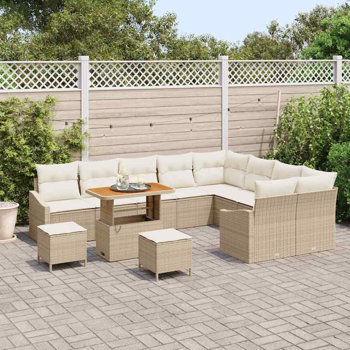 Set di sedute per esterni con cuscini beige e telai in vimini. Sono presenti un tavolo e due pouf, su un patio con una recinzione.