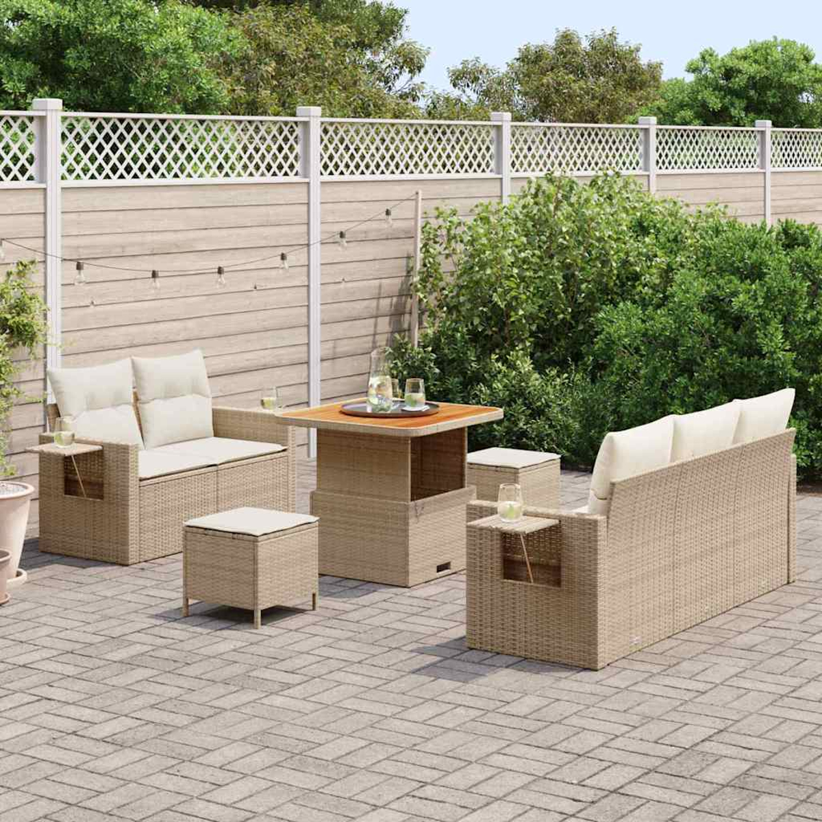 Terrassengarnitur im Freien mit gewebten beigefarbenen Möbeln, darunter ein Sofa, Stühle und ein Tisch, auf einer Ziegelterrasse mit Zaun und Grün.