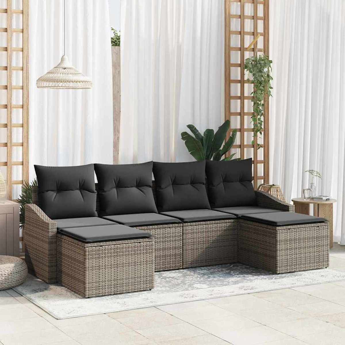 Ein graues Rattan-Ecksofa mit schwarzen Kissen steht auf einem Teppich. Weiße Vorhänge und Holzgitter im Hintergrund.