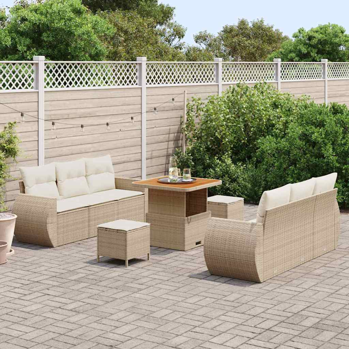 Terrassenmöbel-Set mit Sofa, zwei Stühlen, einem Tisch und zwei Ottomanen. Auf einer Ziegelpflasterung mit Zaun und Grün im Hintergrund.
