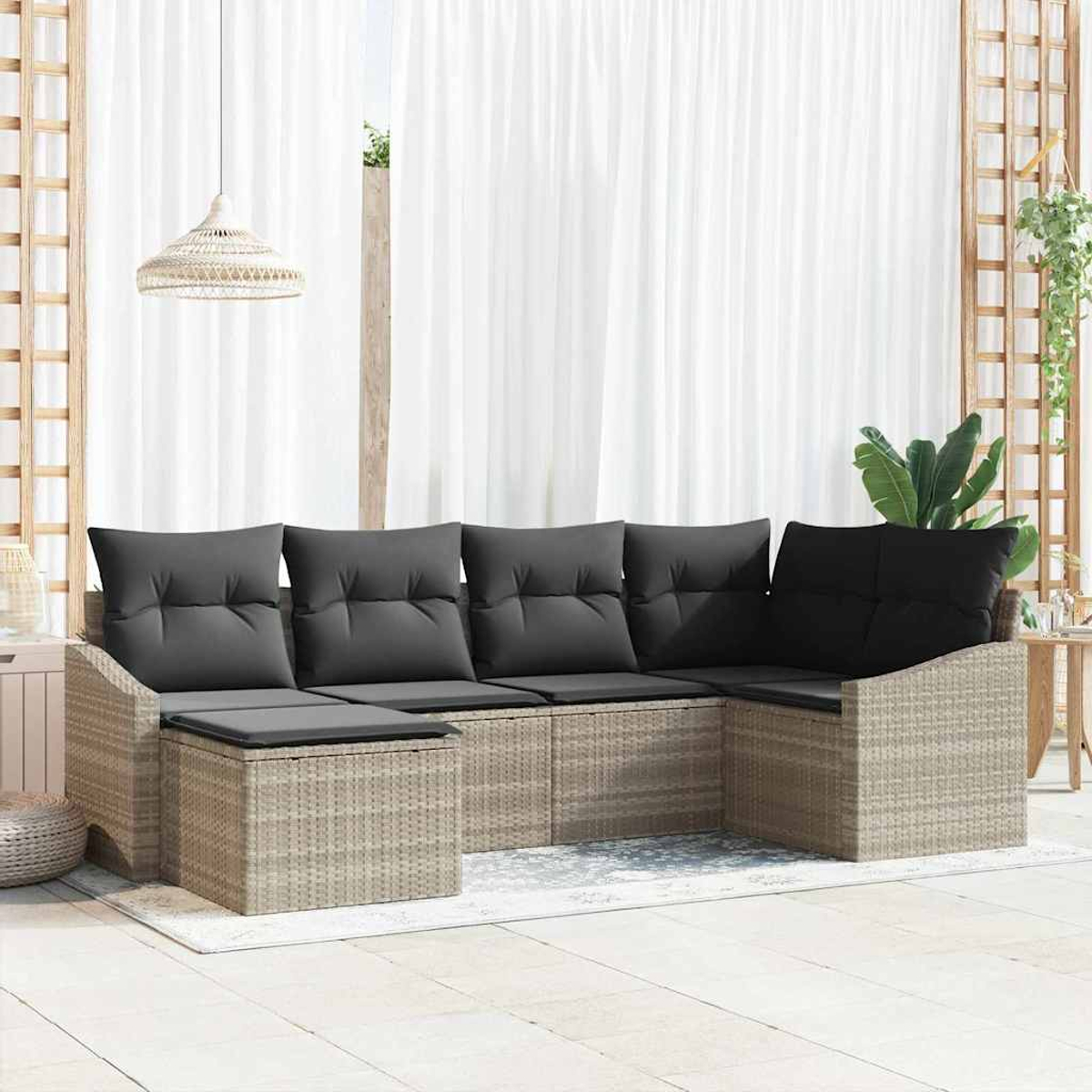 Outdoor-Ecksofa mit grauen Kissen. Gewebter beiger Rahmen auf einer weißen Terrasse. Weiße Vorhänge im Hintergrund.