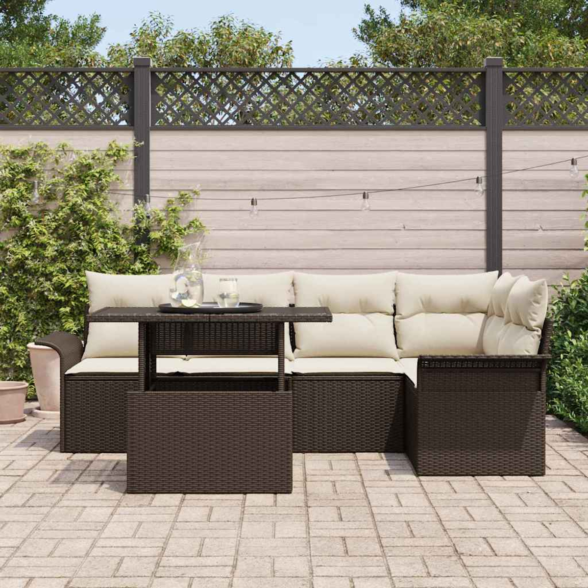 Terrassenset mit braunen gewebten Möbeln und cremefarbenen Kissen. Vor der Garnitur steht ein kleiner Tisch mit Getränken.