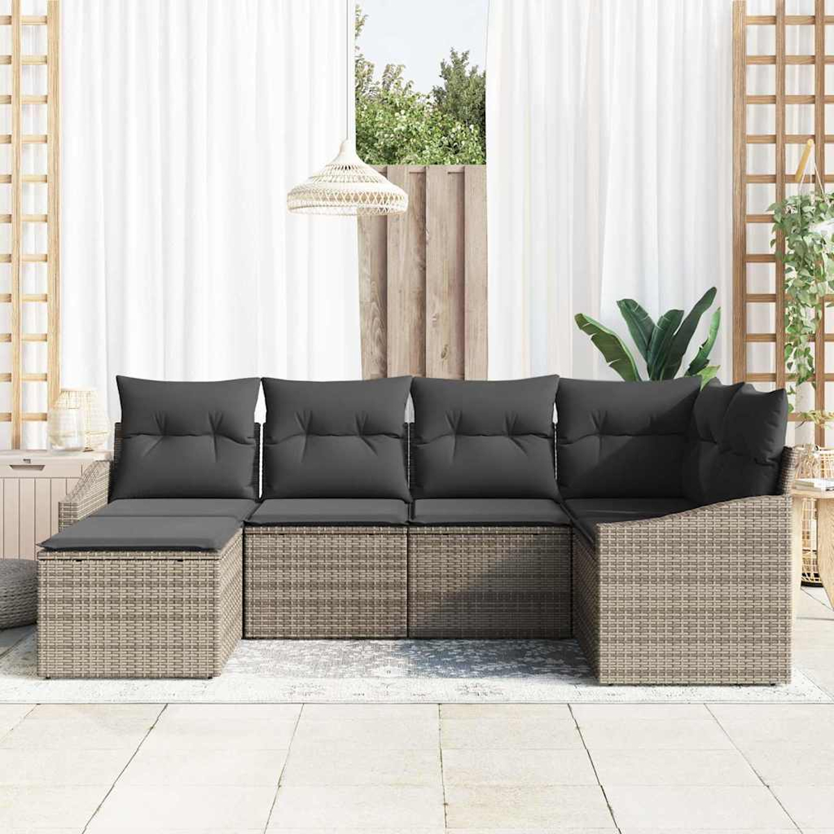 Outdoor-Ecksofa mit grauen Kissen auf einer Terrasse. Weiße Vorhänge, eine gewebte Lampe und Pflanzen sind im Hintergrund zu sehen.