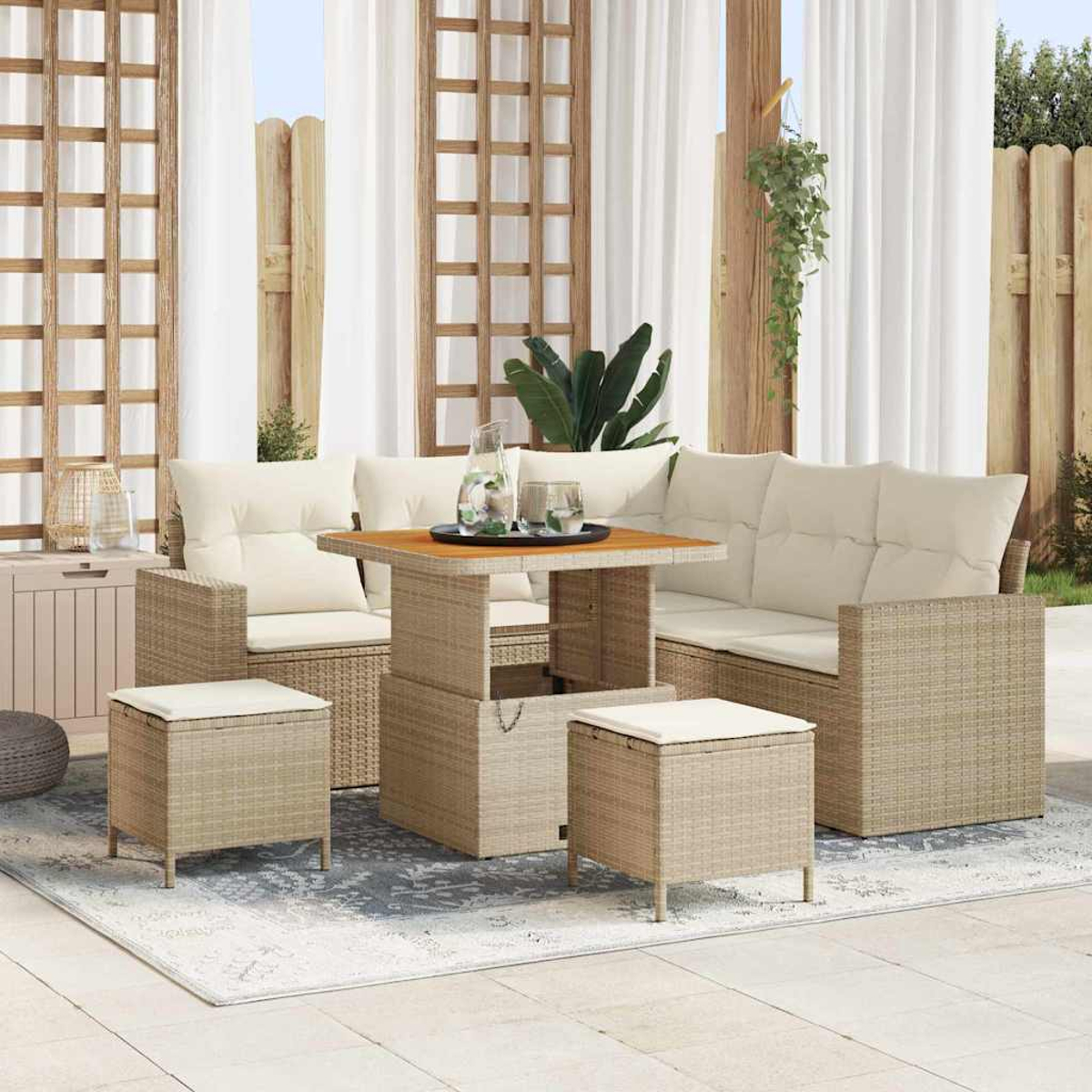 Gartenmöbel-Set mit beigefarbenen Korbmöbeln, weißen Kissen, einem quadratischen Tisch und zwei Ottomanen auf einem Teppich, mit Vorhängen.