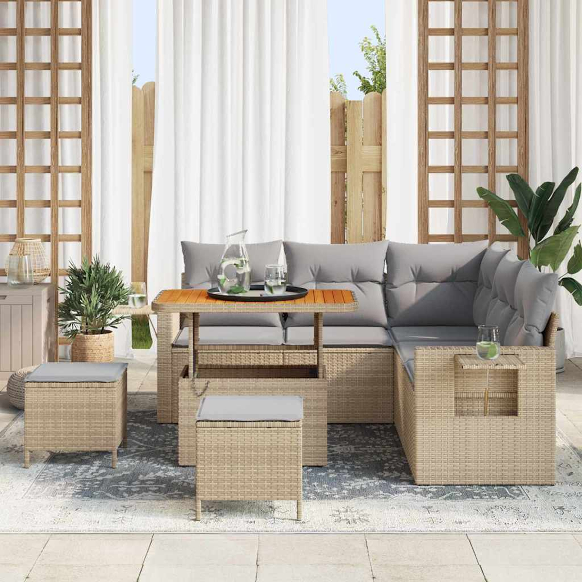 Gartenmöbel-Set aus Korbgeflecht mit Tisch, Kissen und zwei Ottomanen. Weiße Vorhänge und Holzgitter im Hintergrund.