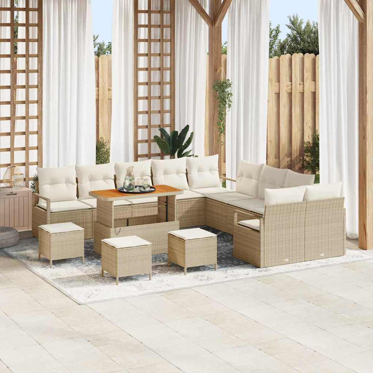 Outdoor-Sitzbereich mit beigen Korbmöbeln und weißen Kissen. Ein Couchtisch mit Gläsern. Weiße Vorhänge und Holzkonstruktion.