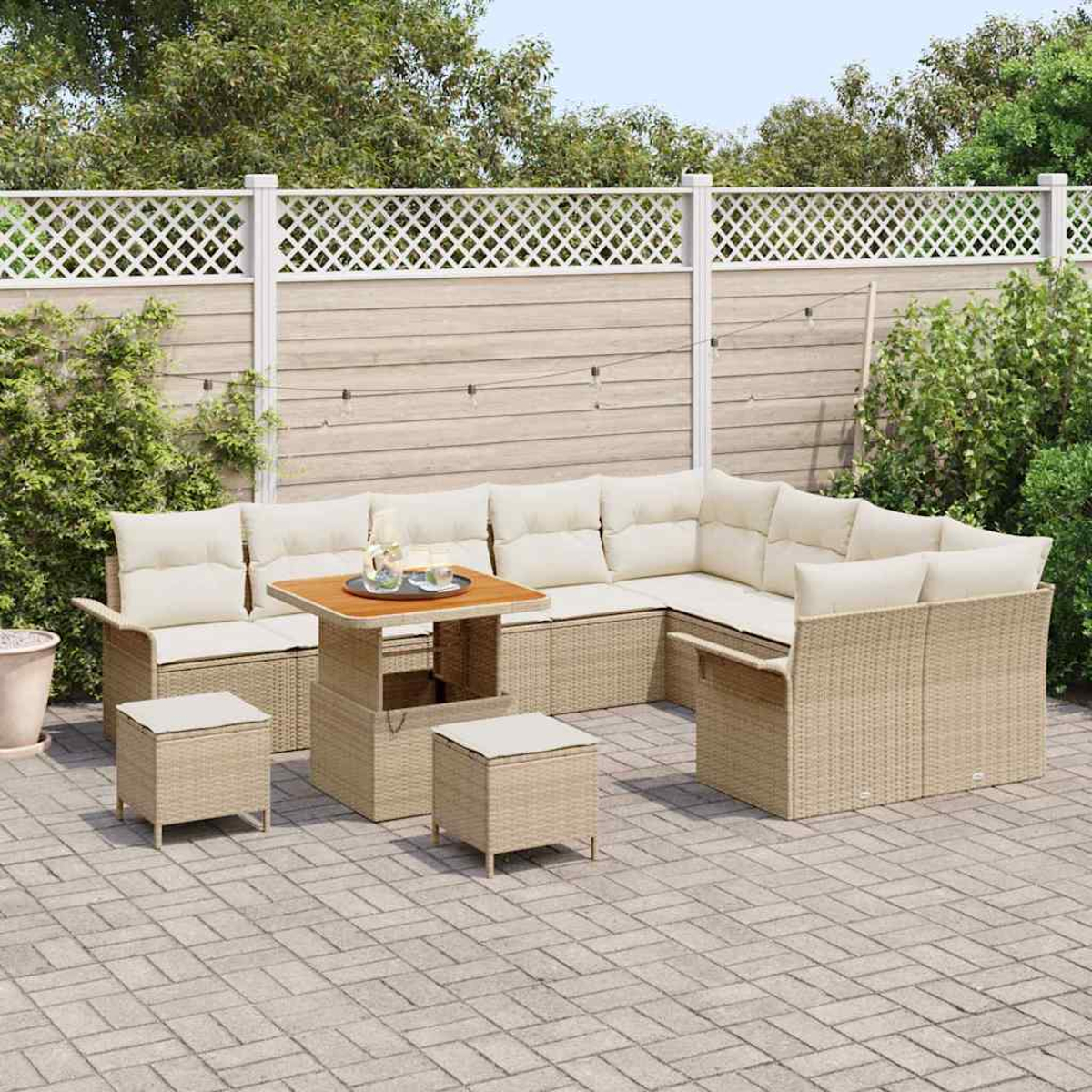 Gartenmöbel-Set aus Korbgeflecht mit beigen Kissen. Enthält einen Tisch, Hocker und ein Ecksofa, auf einer Backstein-Terrasse.