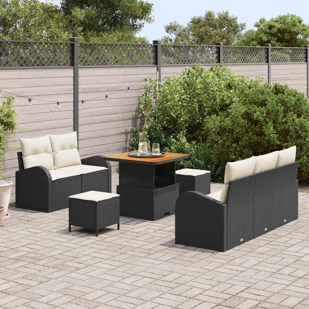 Set per patio esterno con mobili in vimini neri, cuscini color crema, tavolo quadrato e sgabelli su un patio in mattoni.