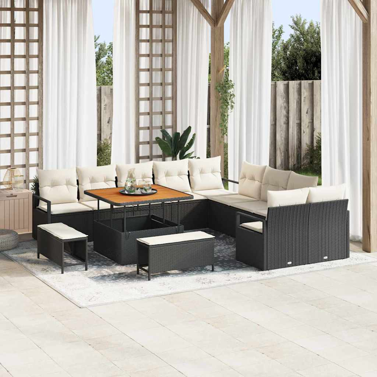 Garten-Sitzgruppe mit schwarzen Korbmöbeln, beigen Kissen, einem Holztisch und weißen Vorhängen auf einer Terrasse.