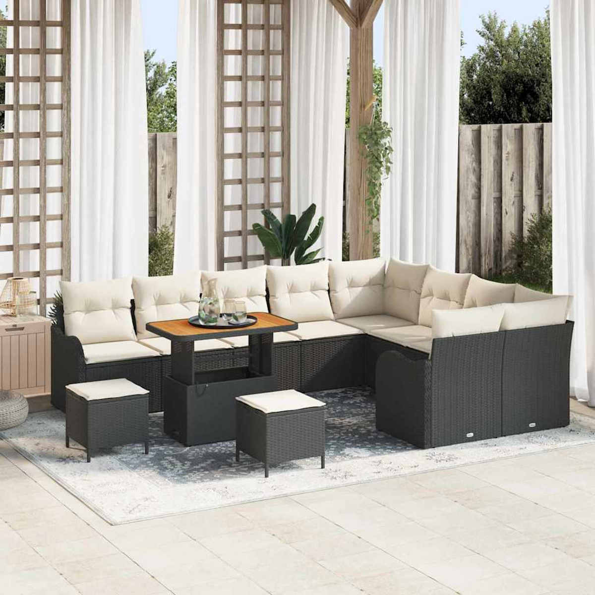 Outdoor-Ecksofa mit beigen Kissen und schwarzem Korbgewebe. Davor steht ein kleiner Tisch mit Getränken. Weiße Vorhänge und ein Teppich sind vorhanden.