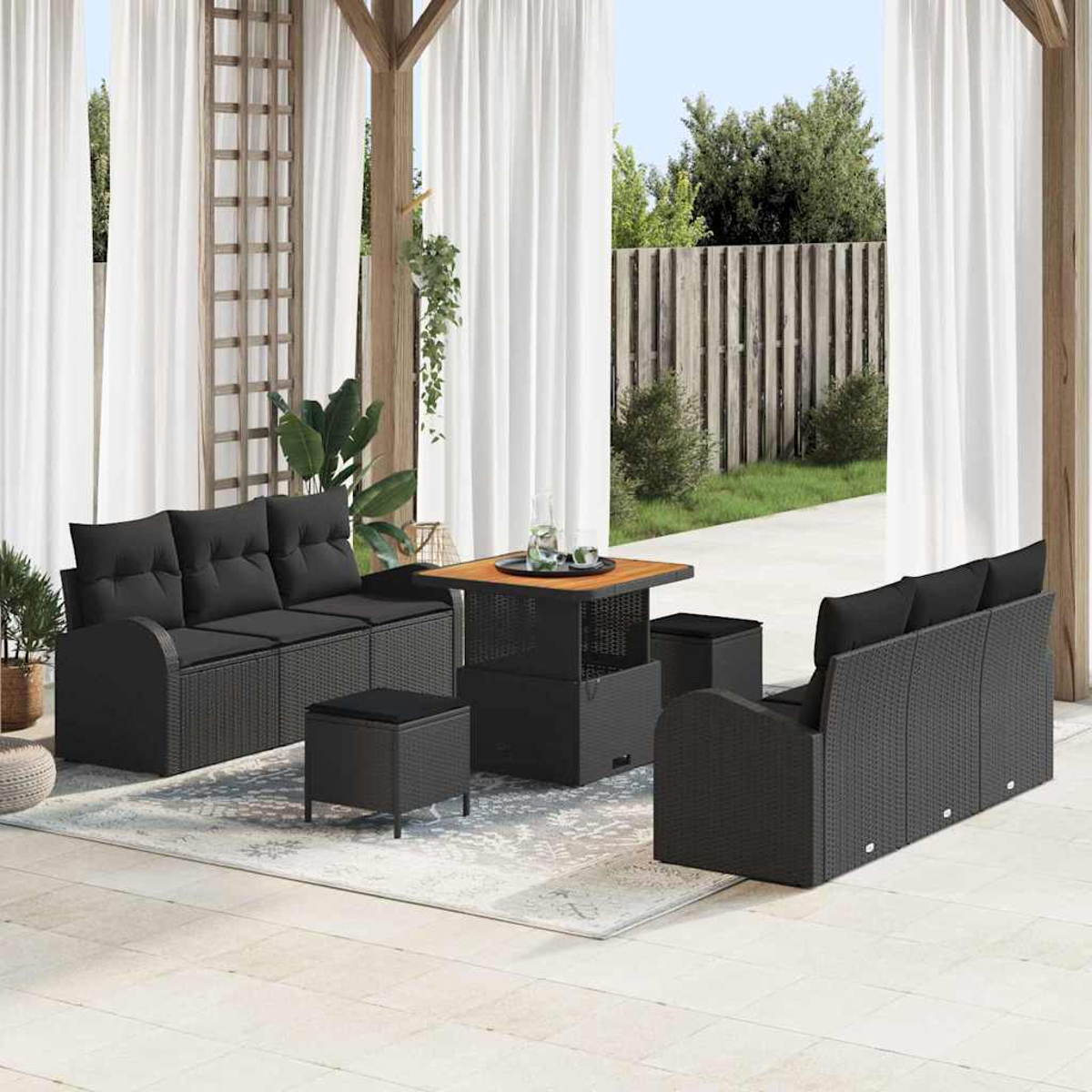 Sitzbereich im Freien mit schwarzen Korbmöbeln, darunter Sofas, Hocker und ein Tisch, auf einem hellen Teppich.