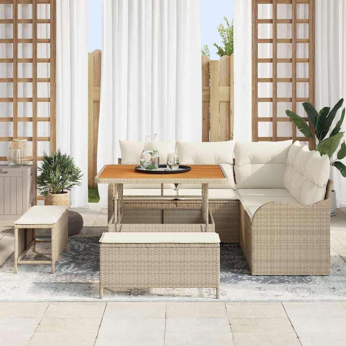 Outdoor-Sitzbereich mit Tisch, Kissen und Pflanzen. Enthält Vorhänge, einen Teppich und einen Holzzaun im Hintergrund.