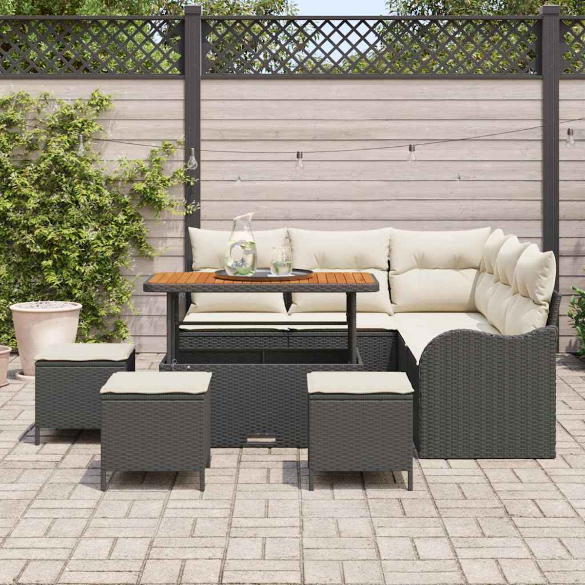 Outdoor-Ecksofa mit cremefarbenen Kissen und einem Holztisch. Enthält drei Ottomanen. Vor einem Holzzaun mit Grün.