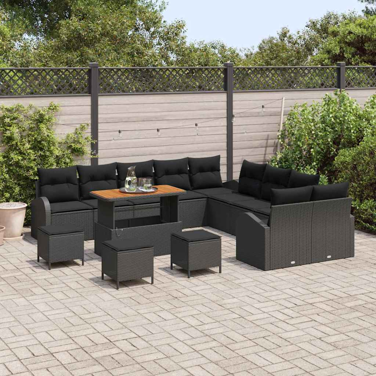 Conjunto de asientos al aire libre con cojines negros y mimbre gris. Incluye mesa, otomanas y fondo de valla y vegetación.