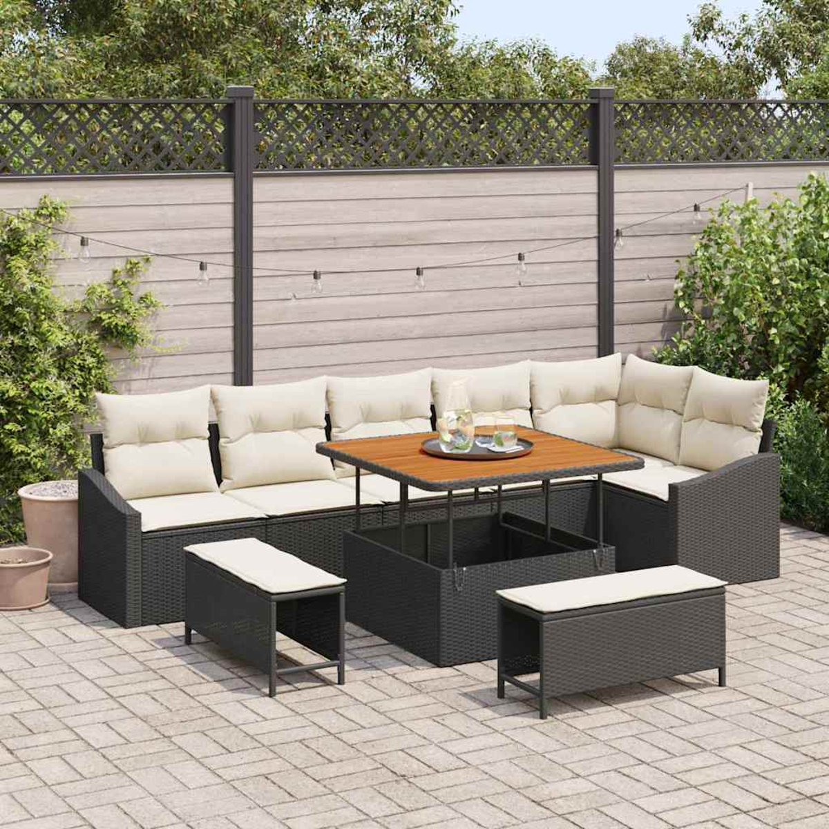 Set per patio esterno con tavolo in legno, sedute e panche. La scena è ambientata su un patio in mattoni con una recinzione e vegetazione sullo sfondo.