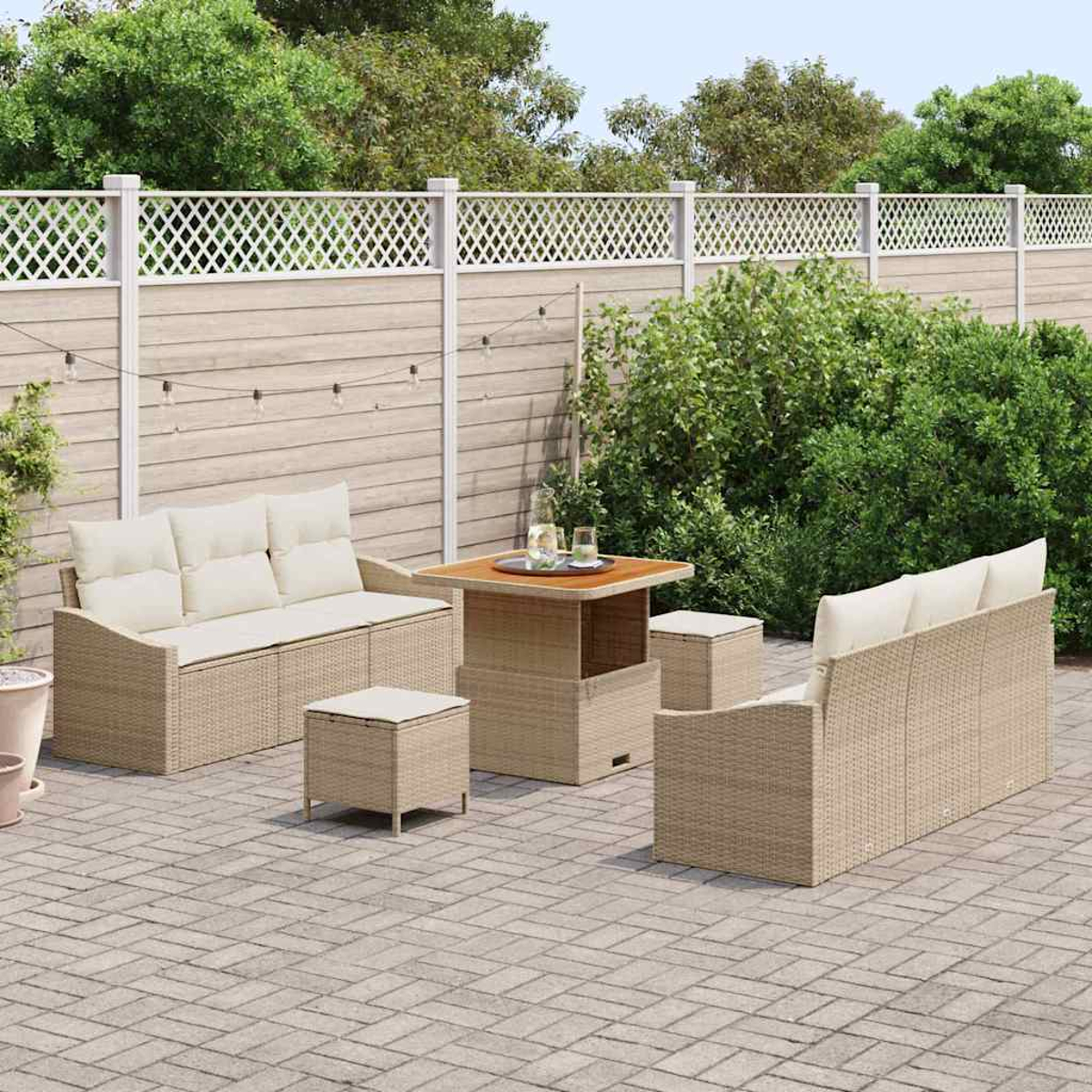 Garten-Terrassenset mit beigefarbenen Sofas, Ottomanen und Tisch auf einer Ziegelterrasse. Ein weißer Zaun und Grünzeug im Hintergrund.