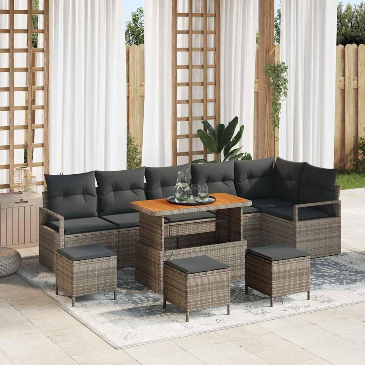 Juego de muebles de patio. Incluye sofá seccional, otomanas y mesa con bandeja. La escena es frente a cortinas blancas.