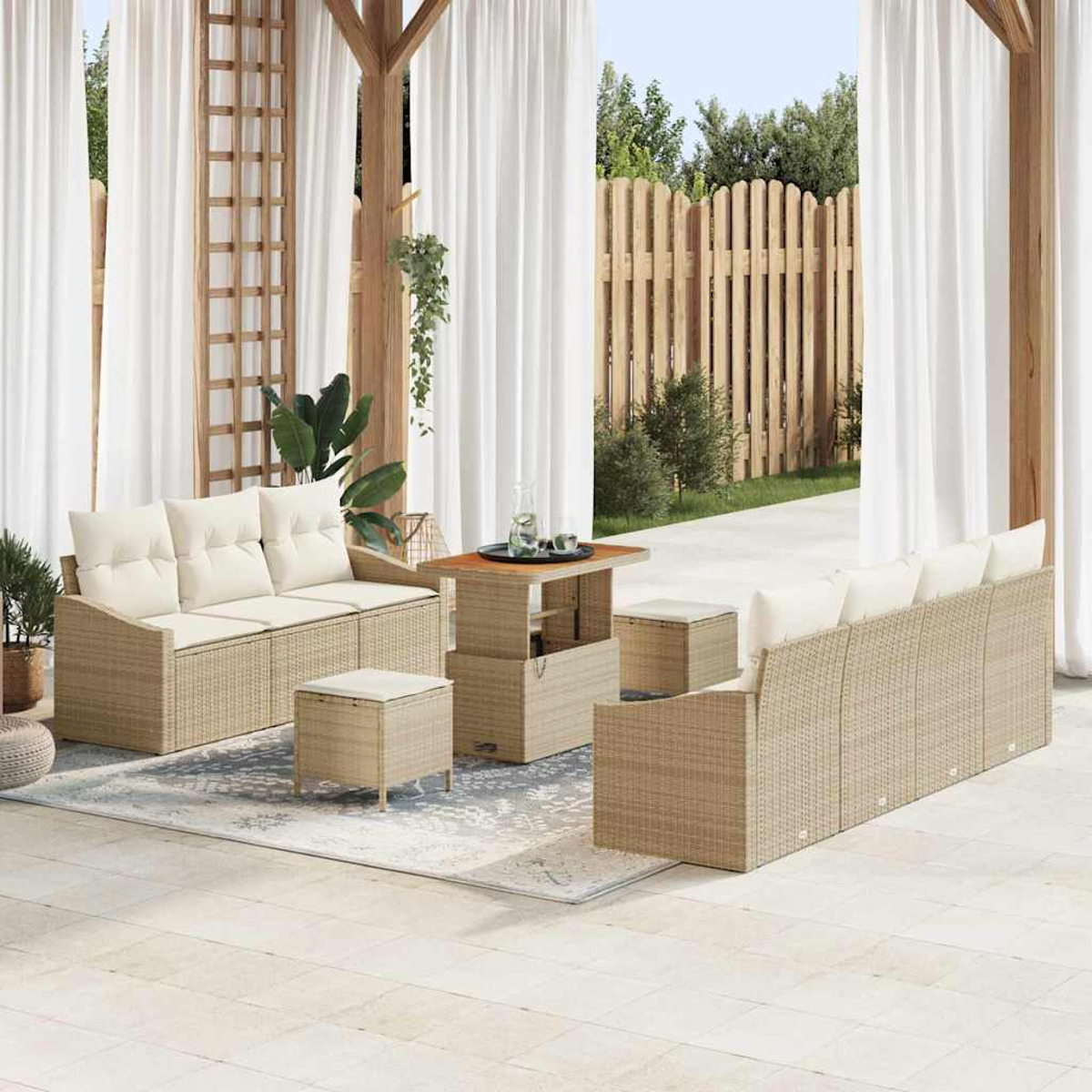 Terrassenset mit beigen Sofas, Ottomanen und Tisch. Weiße Vorhänge, Holzbalken und Holzzaun im Hintergrund.
